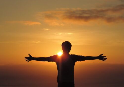a man standing in front of the sun with his arms outstretched